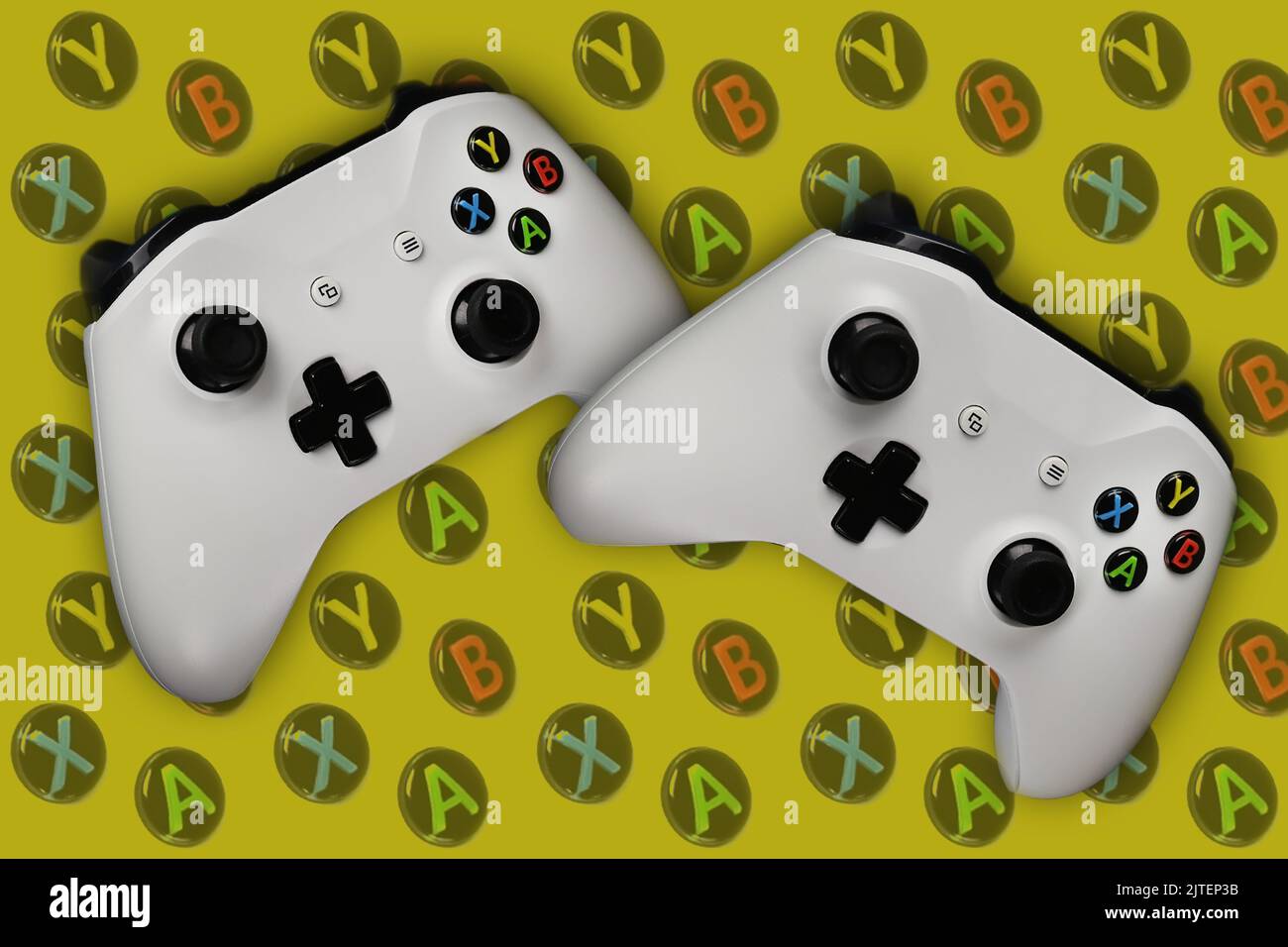 Zwei Spielkonsolen im Flug auf gelbem Hintergrund mit Knöpfen für Spiele Stockfoto