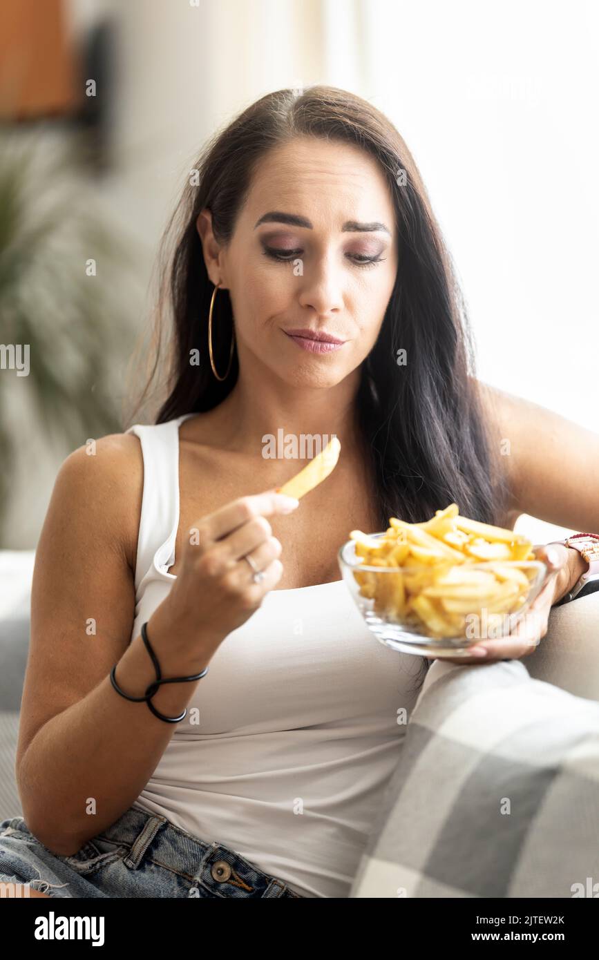 Frau zögert wegen der ungesunden Lebensmittelwirkung dieser Diät, Pommes zu essen. Stockfoto