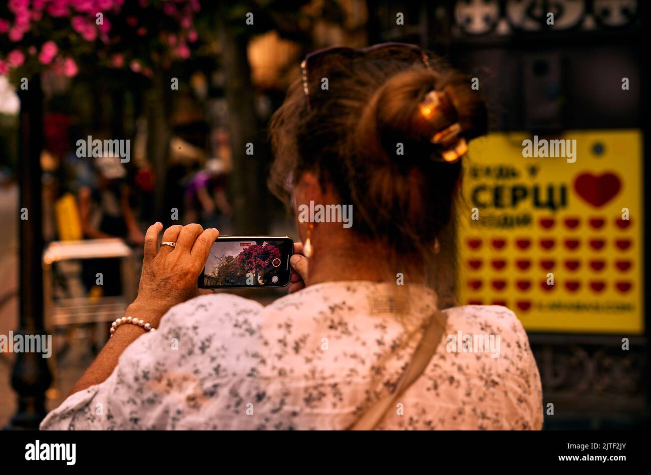 Erwachsene reife Frau, die zur goldenen Stunde ein Video der Stadt auf einem Mobiltelefon schloss. Stockfoto