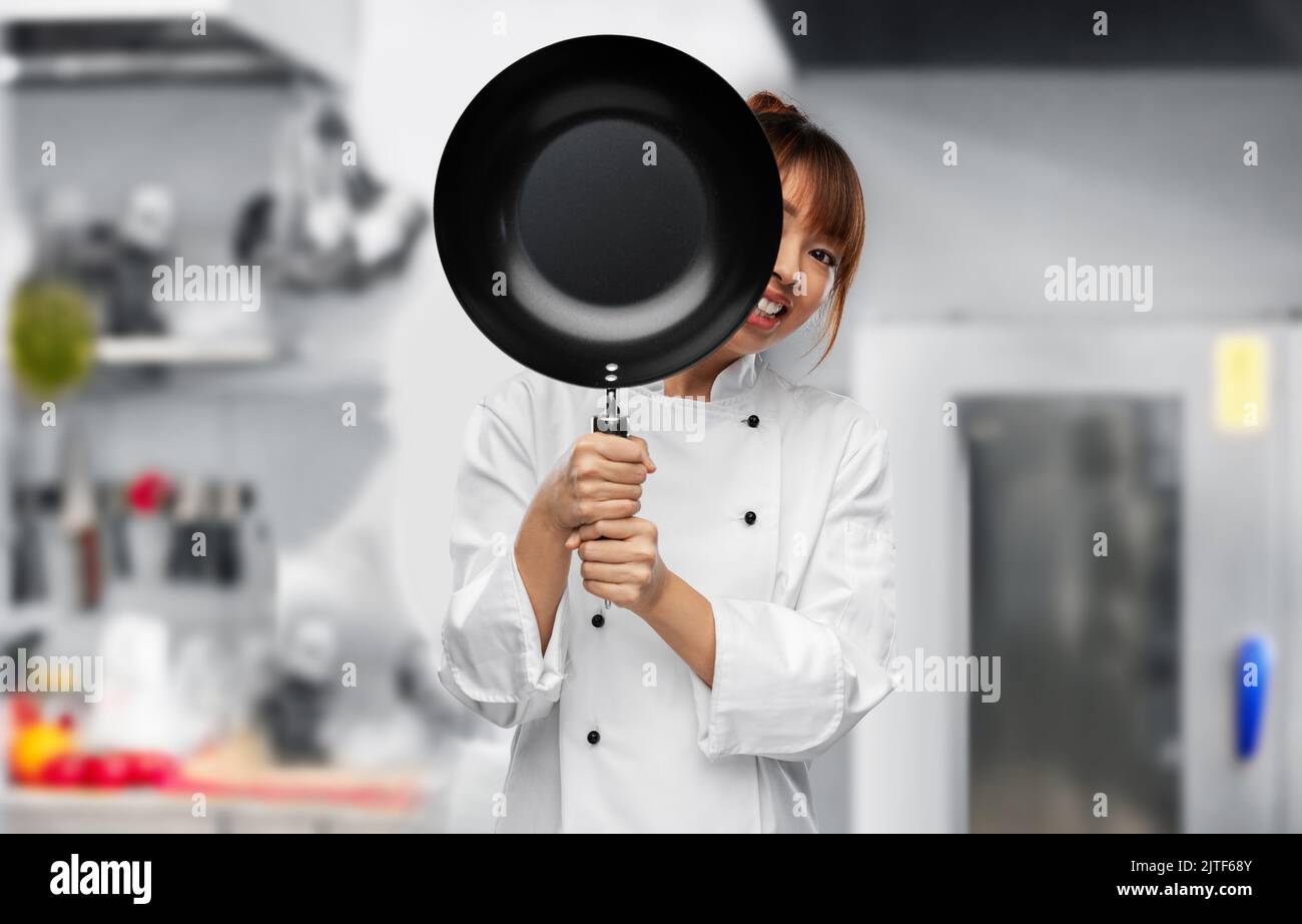 Der Koch guckt hinter der Bratpfanne in die Küche Stockfoto
