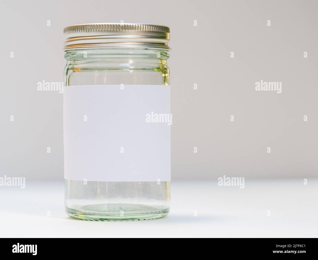 Silberner Glasbecher mit Schraubverschluss und sauberem weißen Etikett Stockfoto