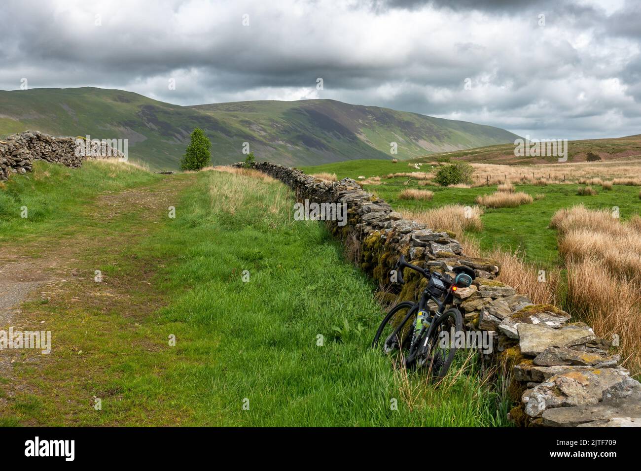 Fahrrad, das sich an einer alten Steinmauer auf einem Reitweg nach Norden in Richtung Calf Top Fell und Caslte Knot, Cumbria, Yorkshire Dales National Park lehnt, Stockfoto