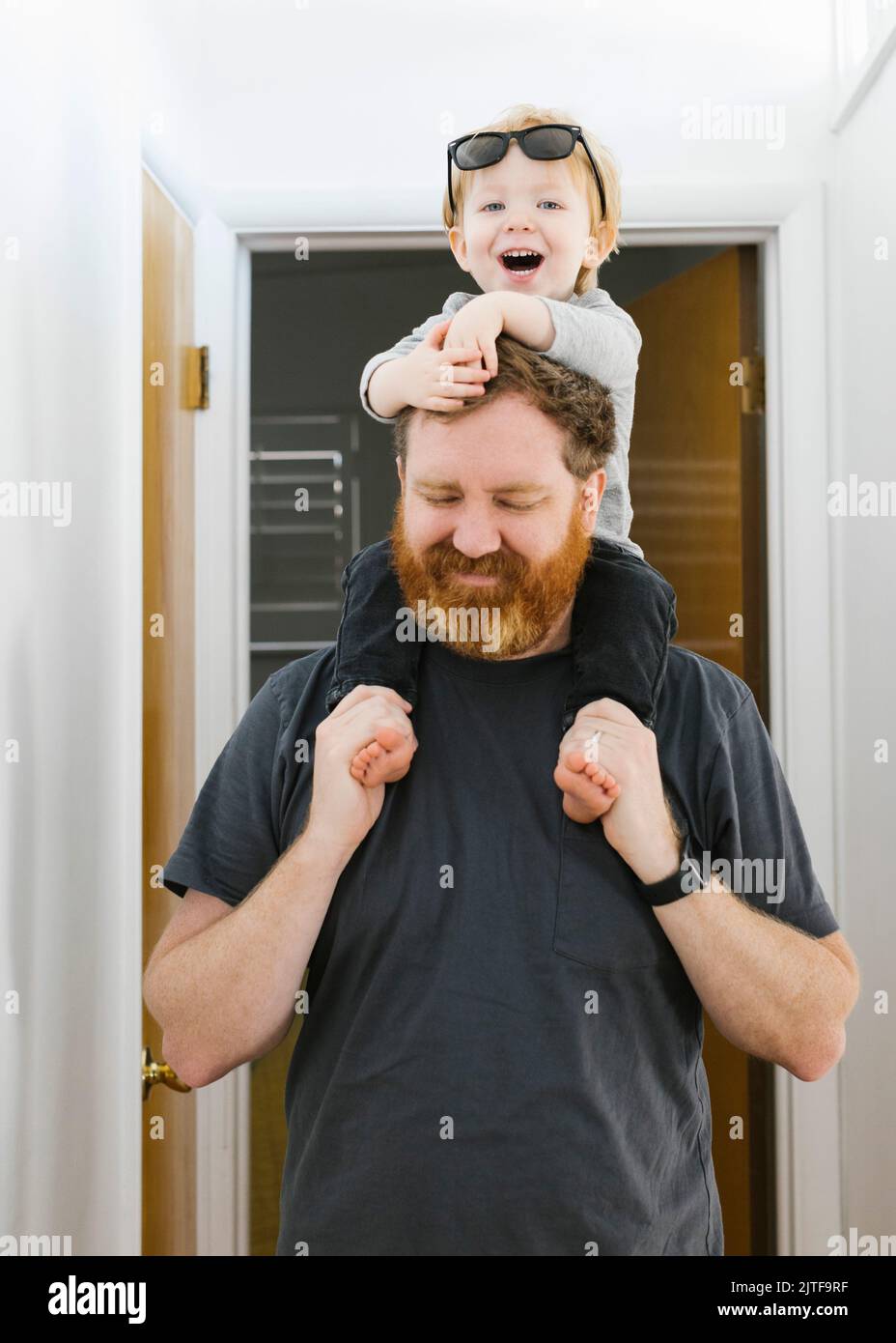 Vater trägt Sohn (2-3) zu Hause auf den Schultern Stockfoto
