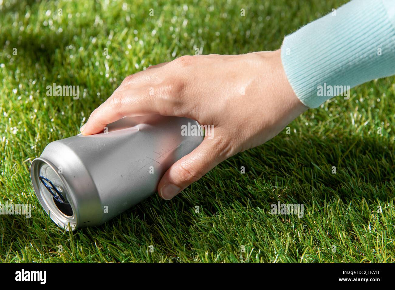 Nahaufnahme der Hand zum Entfernen gebrauchter Blechdosen vom Gras Stockfoto