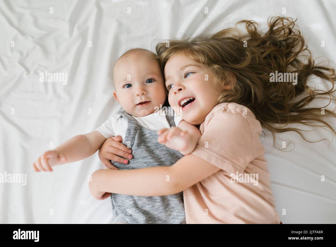 Mädchen (2-3), das den kleinen Bruder umarmt (6-11 Monate) Stockfoto