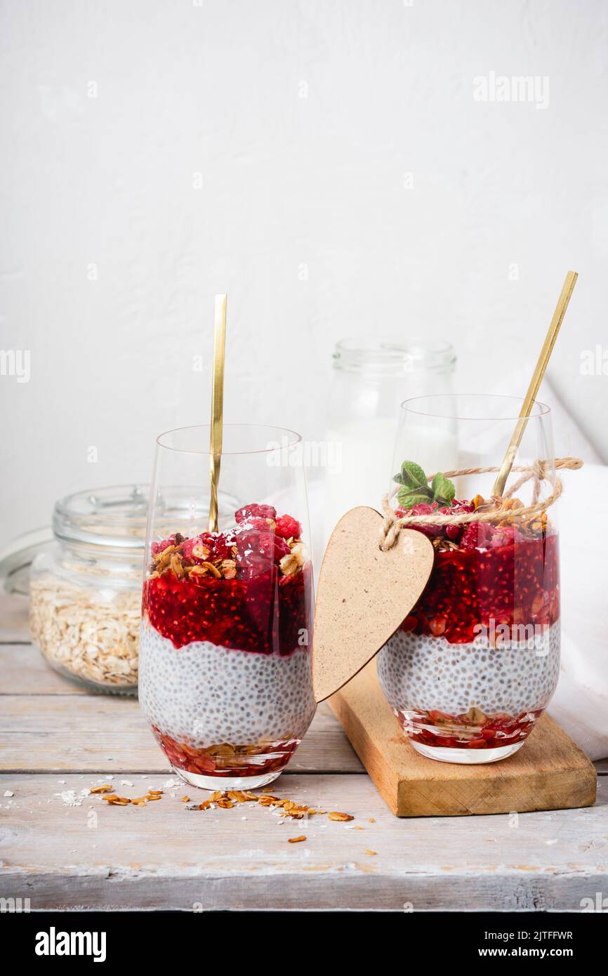 Zwei Gläser Chia Pudding mit Müsli und Himbeeren. Stockfoto