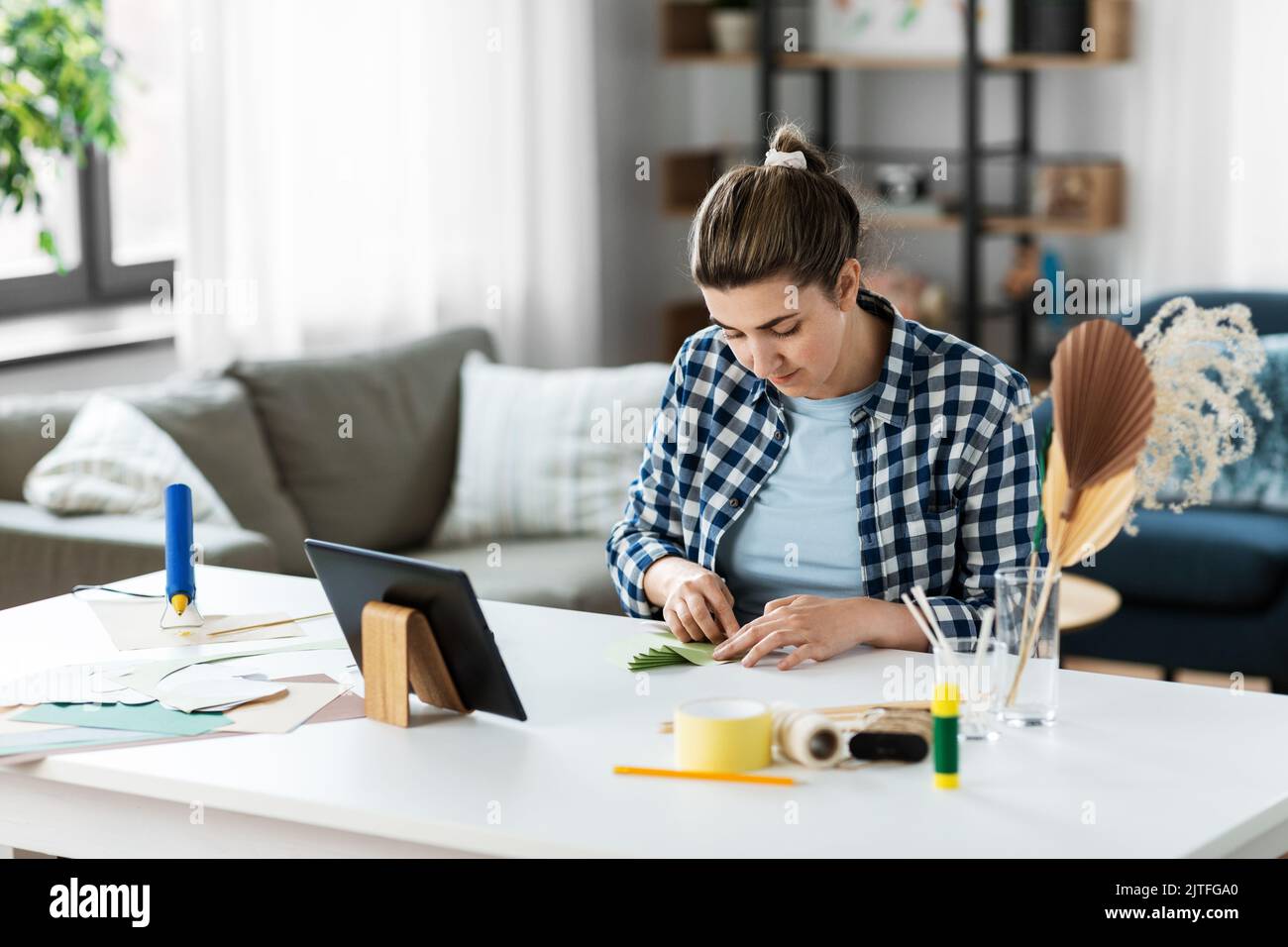 Frau mit Tablet-pc, die zu Hause Papier basteln Stockfotografie - Alamy