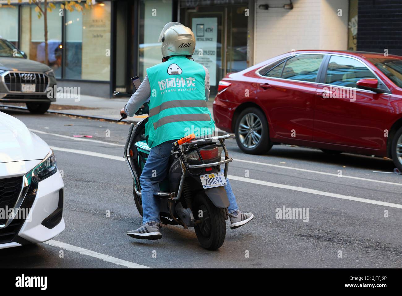 Eine fantuanische Person, die Lebensmittel auf einem elektrischen Moped in New York City geliefert hat. 飯糰外賣 Food Delivery Gig worker. Stockfoto