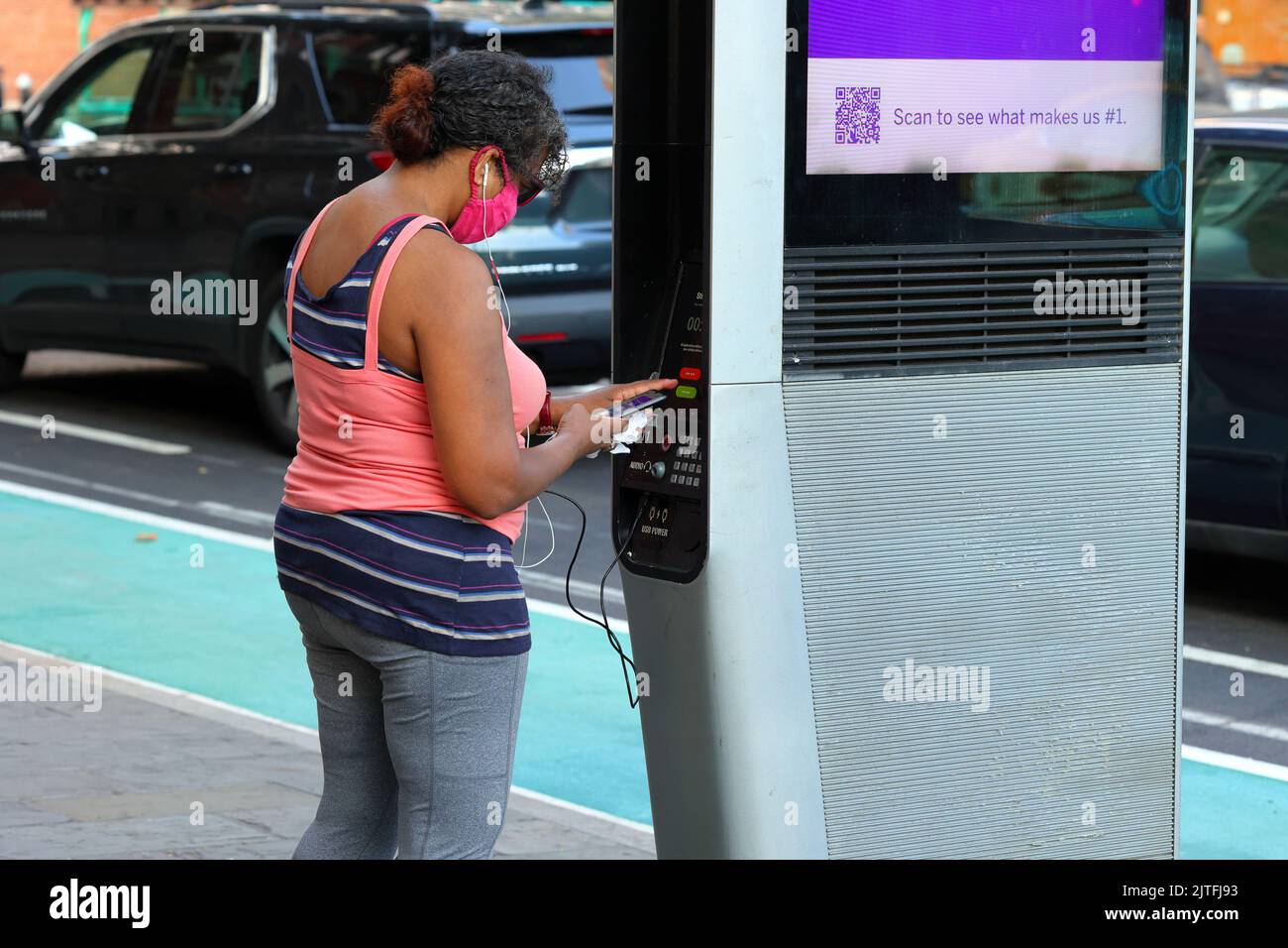 Eine Person, die ihr Smartphone auflädt und das kostenlose WLAN an einem LinkNYC Wi-Fi-Kiosk in New York nutzt. Stockfoto