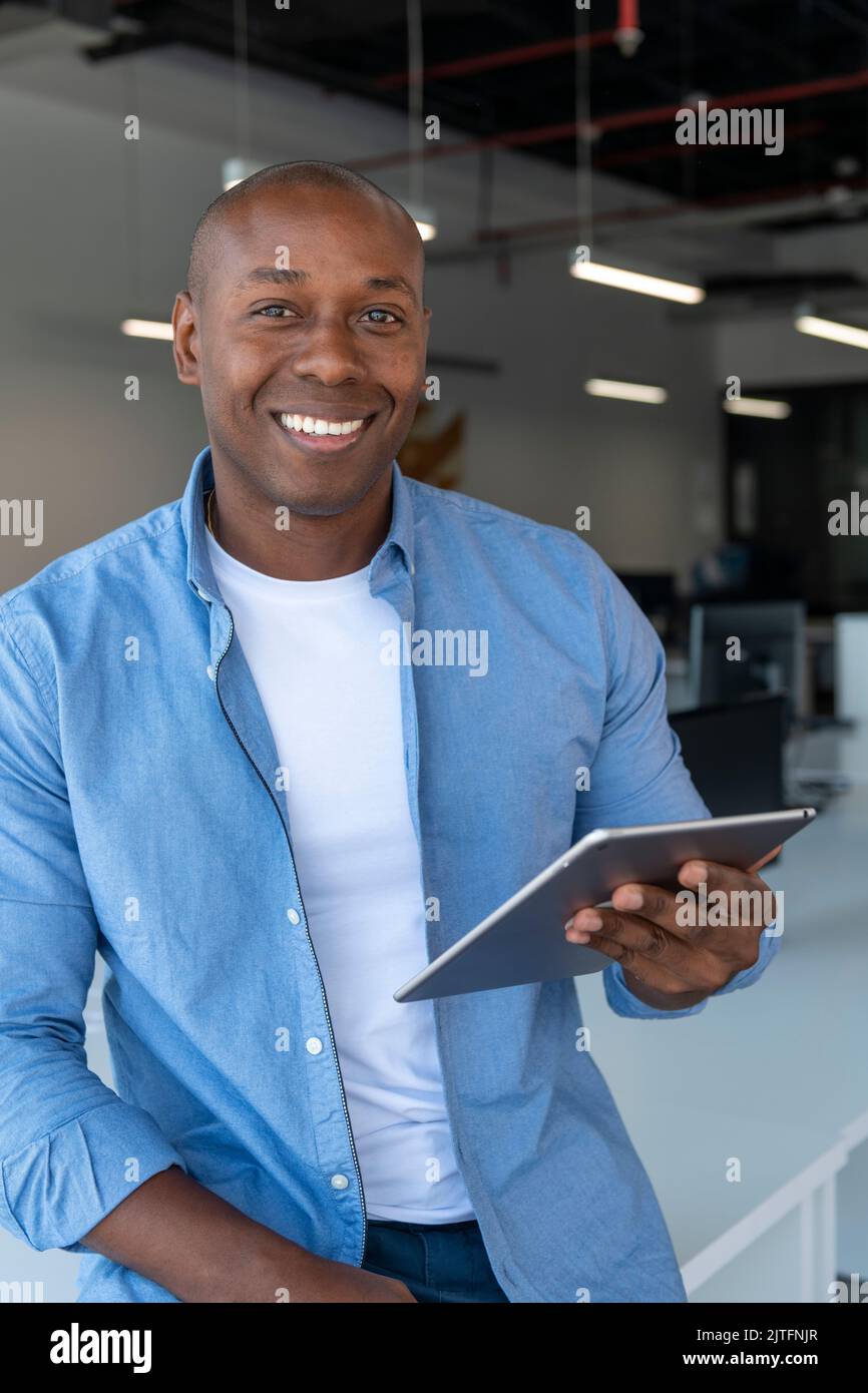 Ausgeschnittene Aufnahme eines jungen Geschäftsmanns, der in seinem Büro steht und ein Tablet benutzt, Spanien Stockfoto