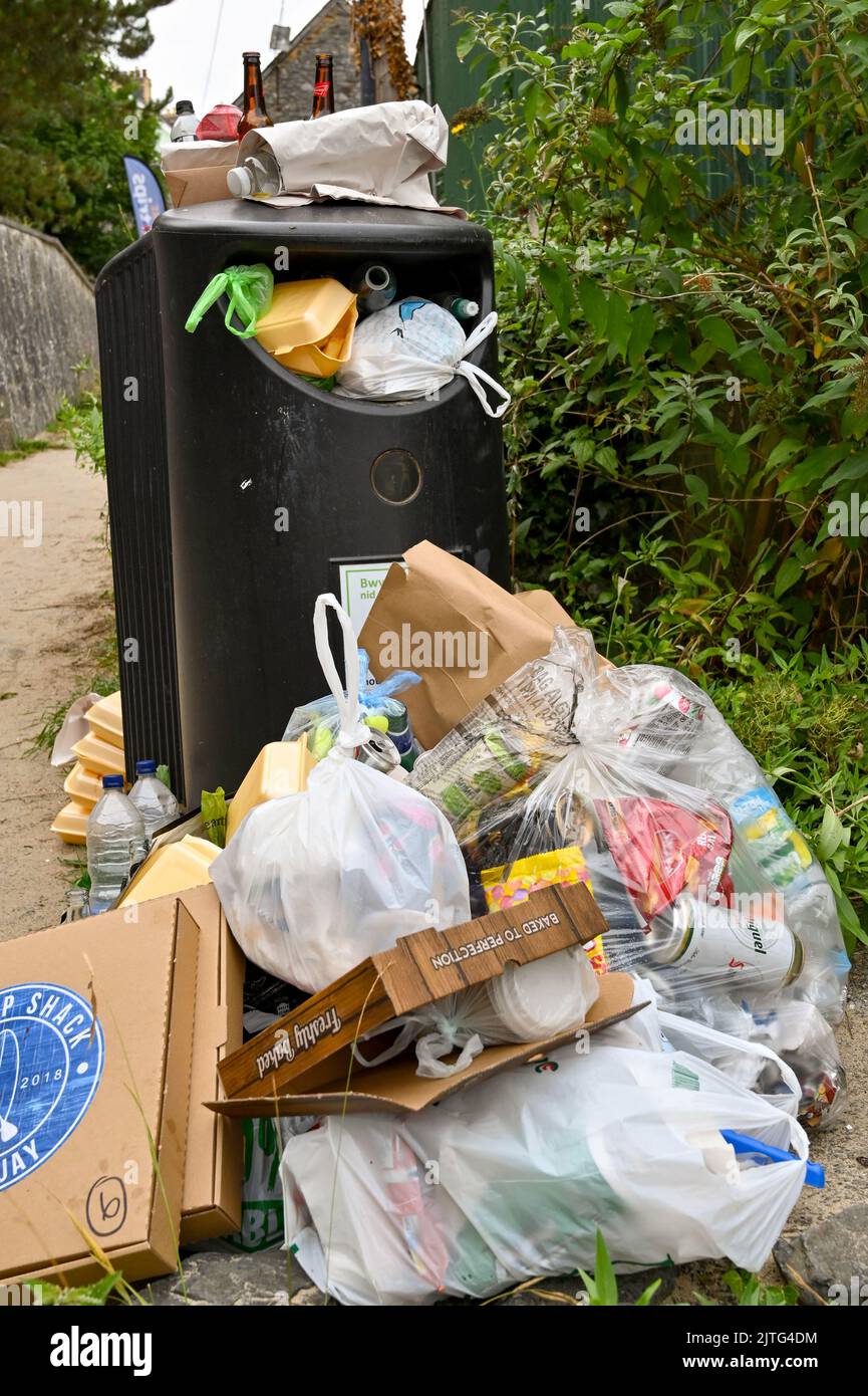 Newquay, Ceredigion, Wales - August 2022: Säcke, Flaschen und andere Abfälle stapelten sich neben einem vollen Abfalleimer Stockfoto