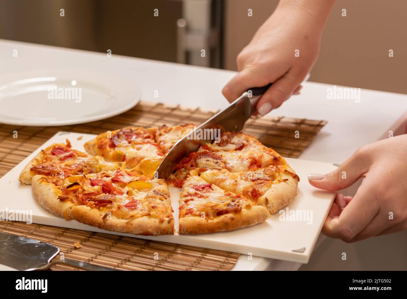 Schneiden Sie Pizza mit einem großen Messer zu Hause aus nächster Nähe Stockfoto