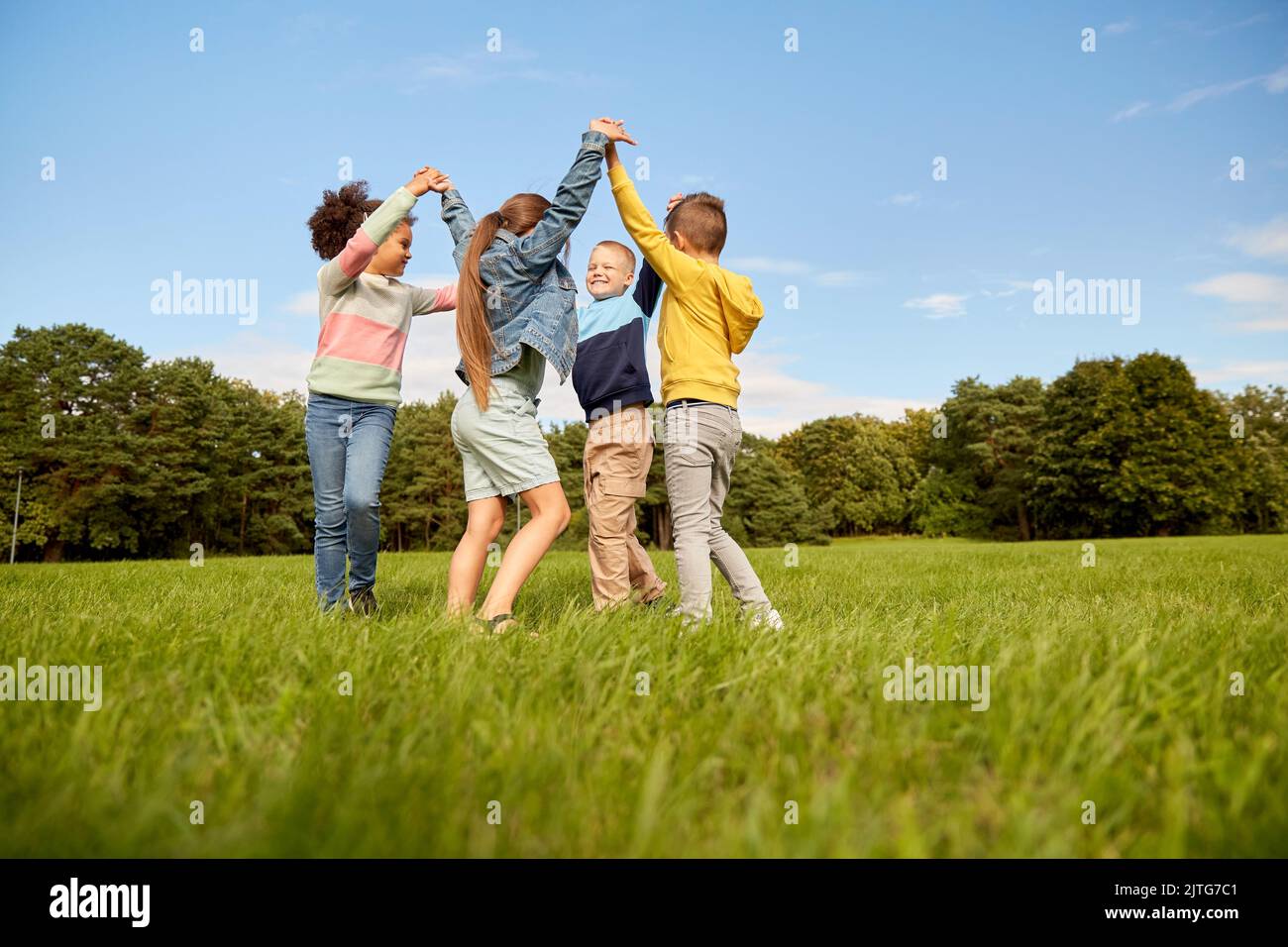 Glückliche Kinder spielen im Park rund tanzen Stockfoto