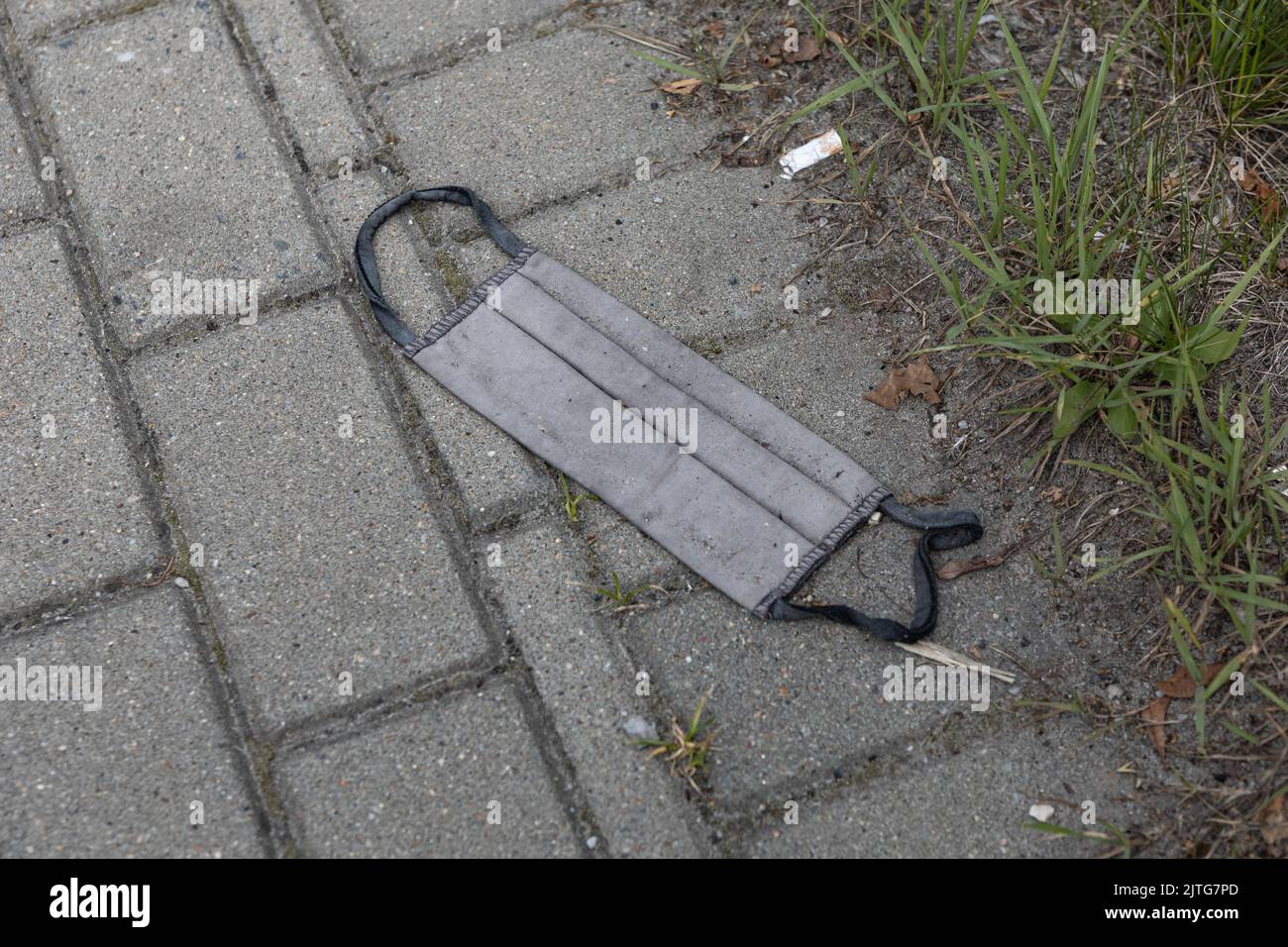 Graue Stoffmaske, abgeflacht auf der Straßenmüll-Textur Stockfoto