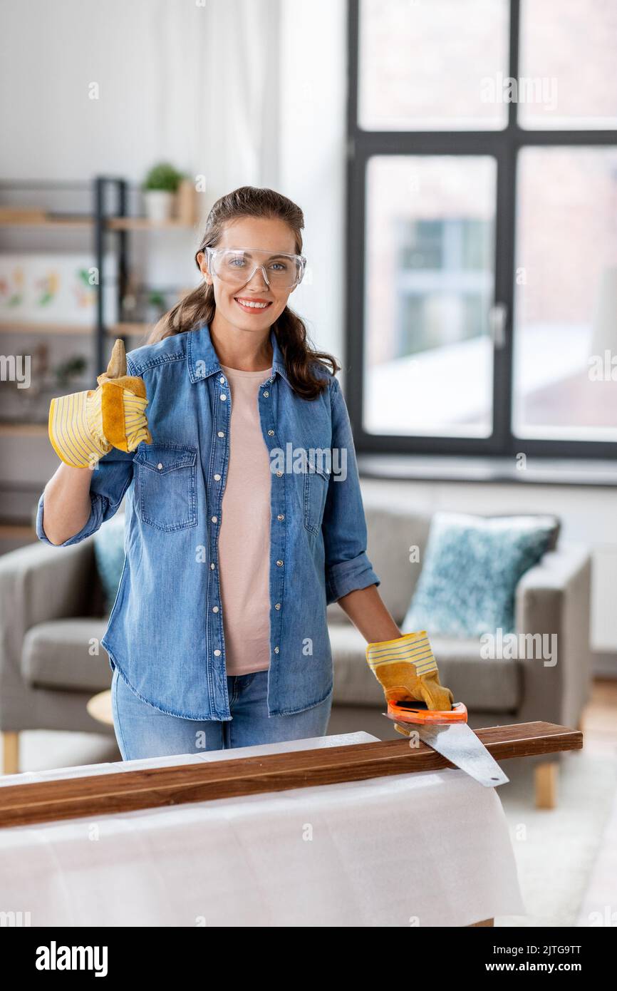 Frau mit Säge, die zu Hause Holzbrett sägt Stockfoto