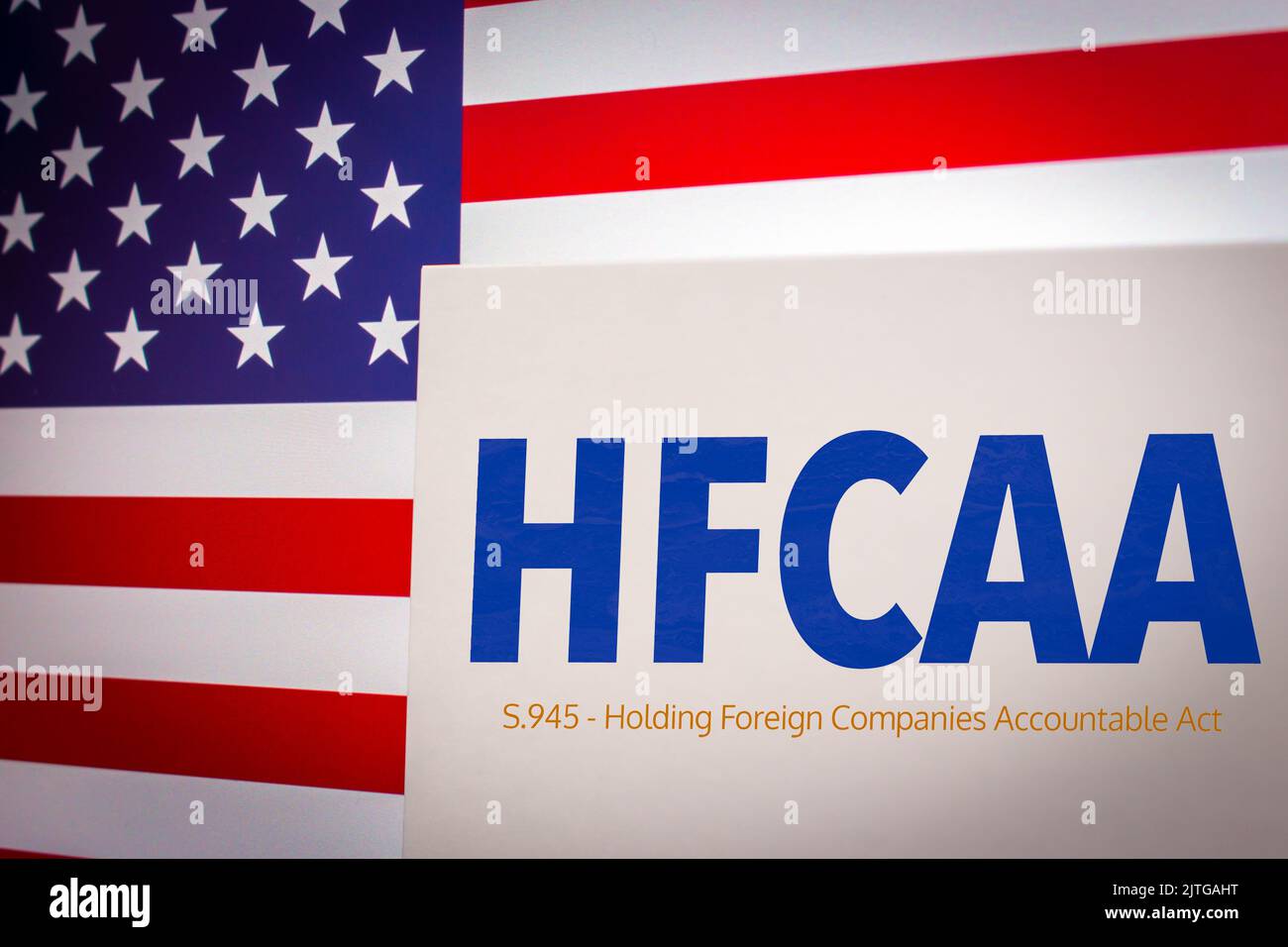 Konzeptionelles Schlüsselwort HFCAA (Holding Foreign Companies Accountable Act) auf der Karte mit US-Flagge. Chinesische Unternehmen in den USA Konzept Stockfoto