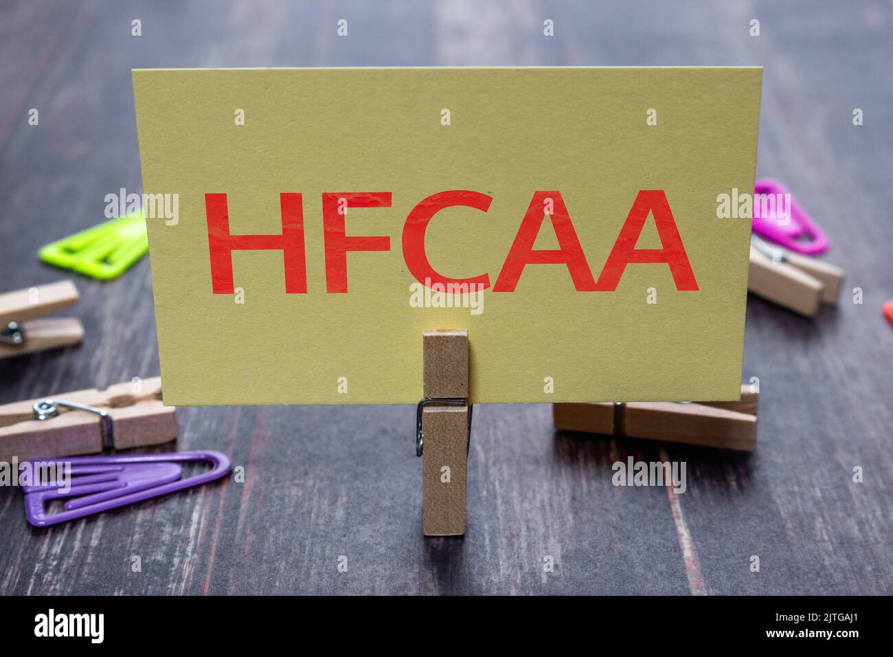 Nachrichtenkarte mit HFCAA (Holding Foreign Companies Accountable Act) mit Holzkinnsel oder natürlicher Holzkneife auf einem schäbigen Holztisch Stockfoto