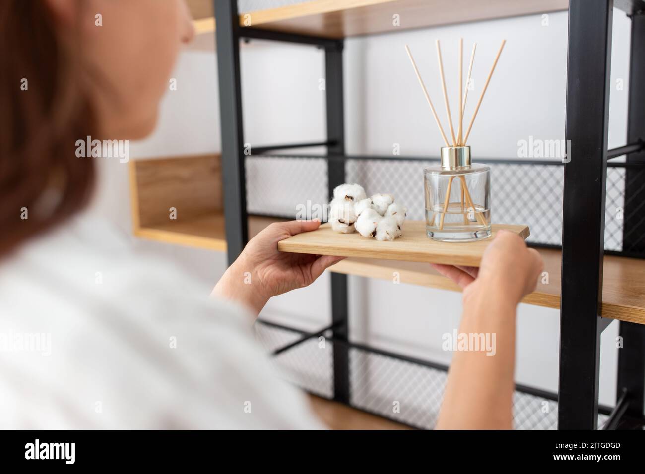 Frau, die den Aroma-Schilf-Diffusor in das Regal stellt Stockfoto