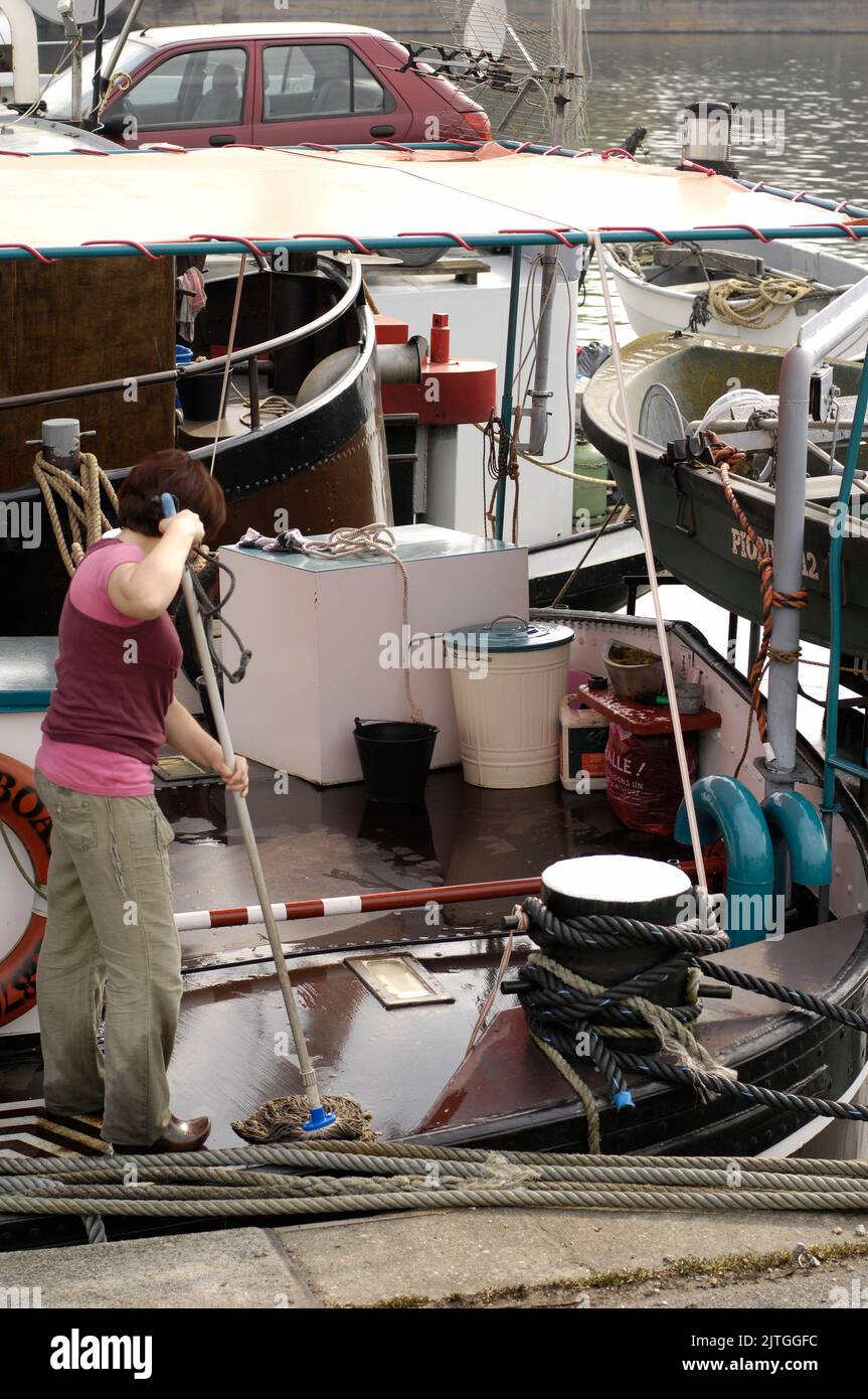 AJAXNETPHOTO. 2011. CONFLANS SAINTE HONORINE, YVELINES, FRANKREICH. - SCHIFFSFORM UND - MOP IN DER HAND, REINIGT EINE FRAU DAS DECK EINER PENICHE, DIE IM HAFEN FESTGEMACHT IST. FOTO: JONATHAN EASTLAND/AJAX REF:D112603 1071 Stockfoto