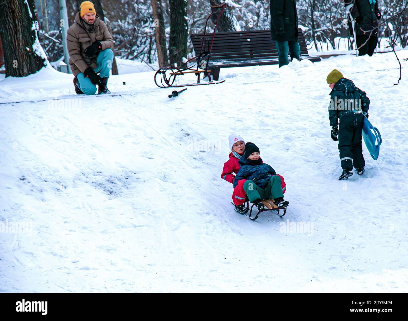 Dnepropetrovsk, Ukraine - 12.31.2021: Kinder und Erwachsene fahren im Winter Schlitten den Hügel hinunter. Spiele im Freien für Kinder. Kindheit, Freizeit und Jahreszeit Stockfoto