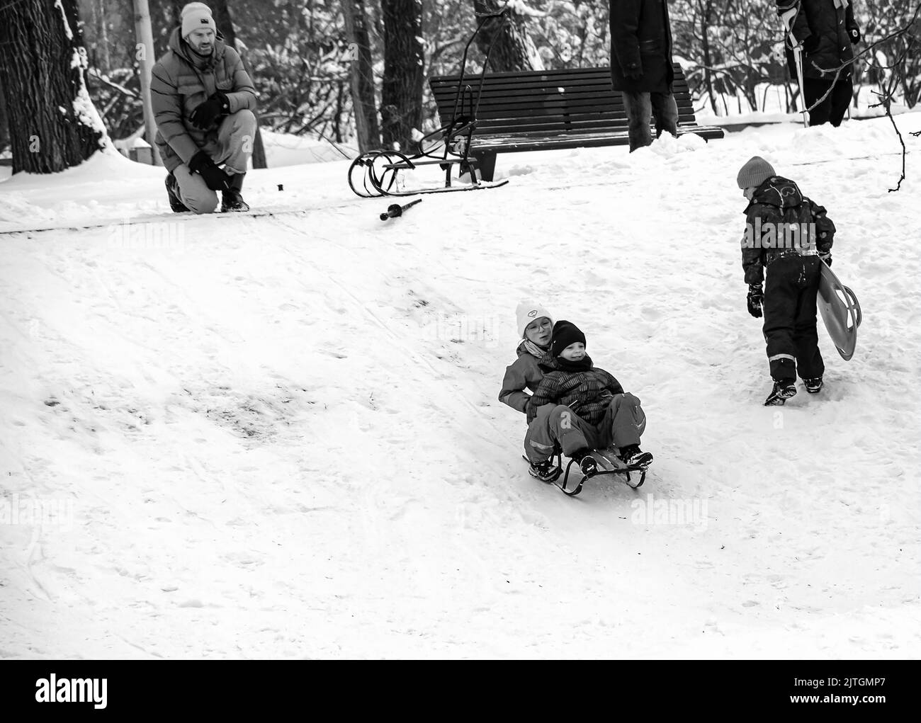 Dnepropetrovsk, Ukraine - 12.31.2021: Kinder und Erwachsene fahren im Winter Schlitten den Hügel hinunter. Spiele im Freien für Kinder. Kindheit, Freizeit und Jahreszeit Stockfoto