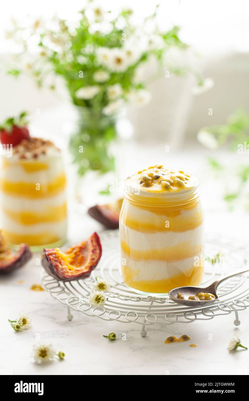 Schichten von Joghurt und Passionsfrucht Quark in kleinen Glasgefäßen. Jedes Dessert wird mit Passionsfrucht-Samen gekrönt. Stockfoto