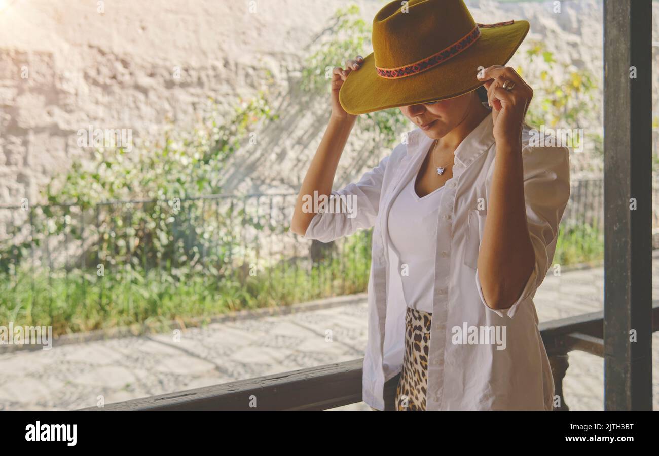 Frau mit Cowboyhut auf der Veranda sitzend, Jalisco Mexiko, Porträt einer glücklichen Frau mit Hut. Selektiver Fokus. Stockfoto