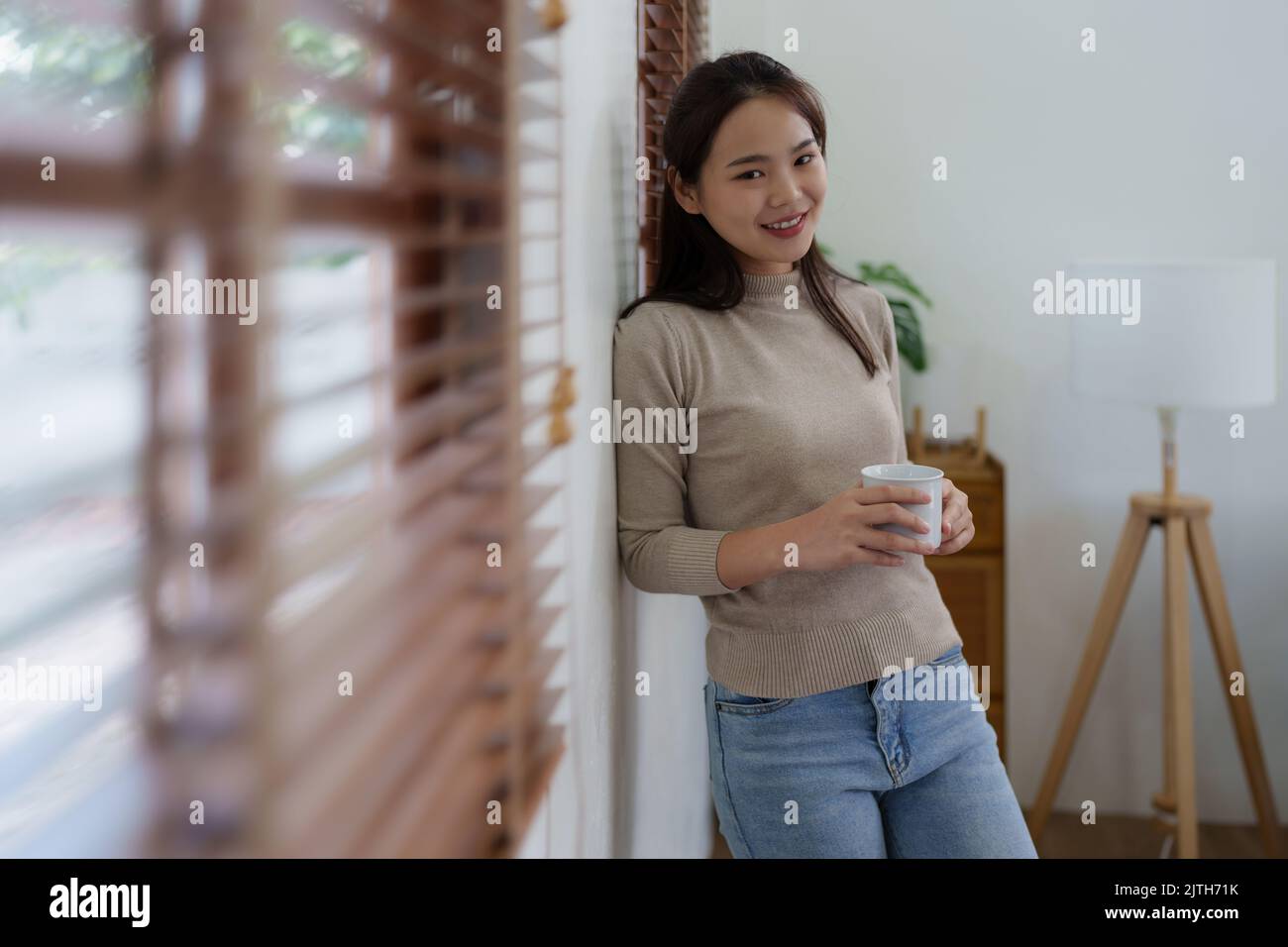 Schöne Frau, die sich zu Hause entspannt und morgens Kaffee trinkt Stockfoto