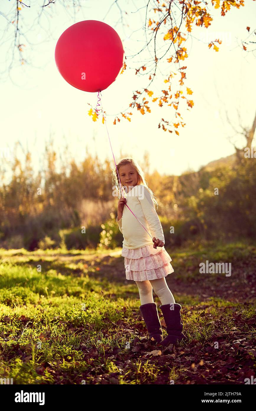 Der Spaß der Kindheit. Porträt eines jungen Mädchens, das draußen mit einem Ballon spielt. Stockfoto