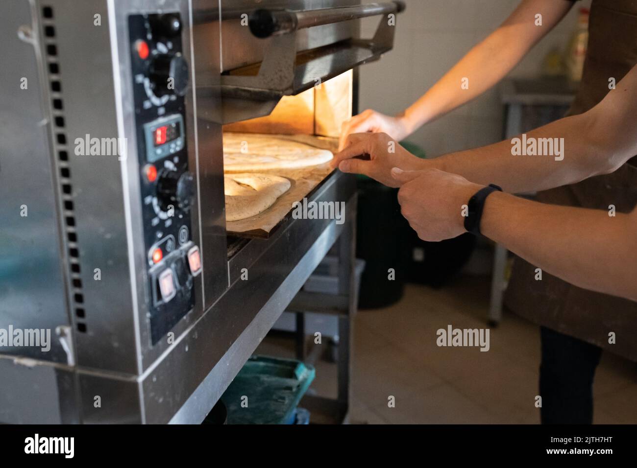 Eine Frau in einer Bäckerei stellt traditionelles französisches Fougasse-Brot aus dem Ofen. Vorderansicht. Stockfoto