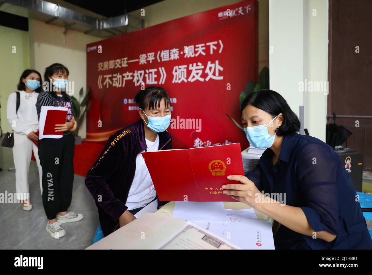 CHONGQING, CHINA - 30. AUGUST 2022 - Hauskäufer (2. R) und Mitarbeiter prüfen in einem neuen Gebäude in Chongqing, CH, die Schutzzertifikate Stockfoto