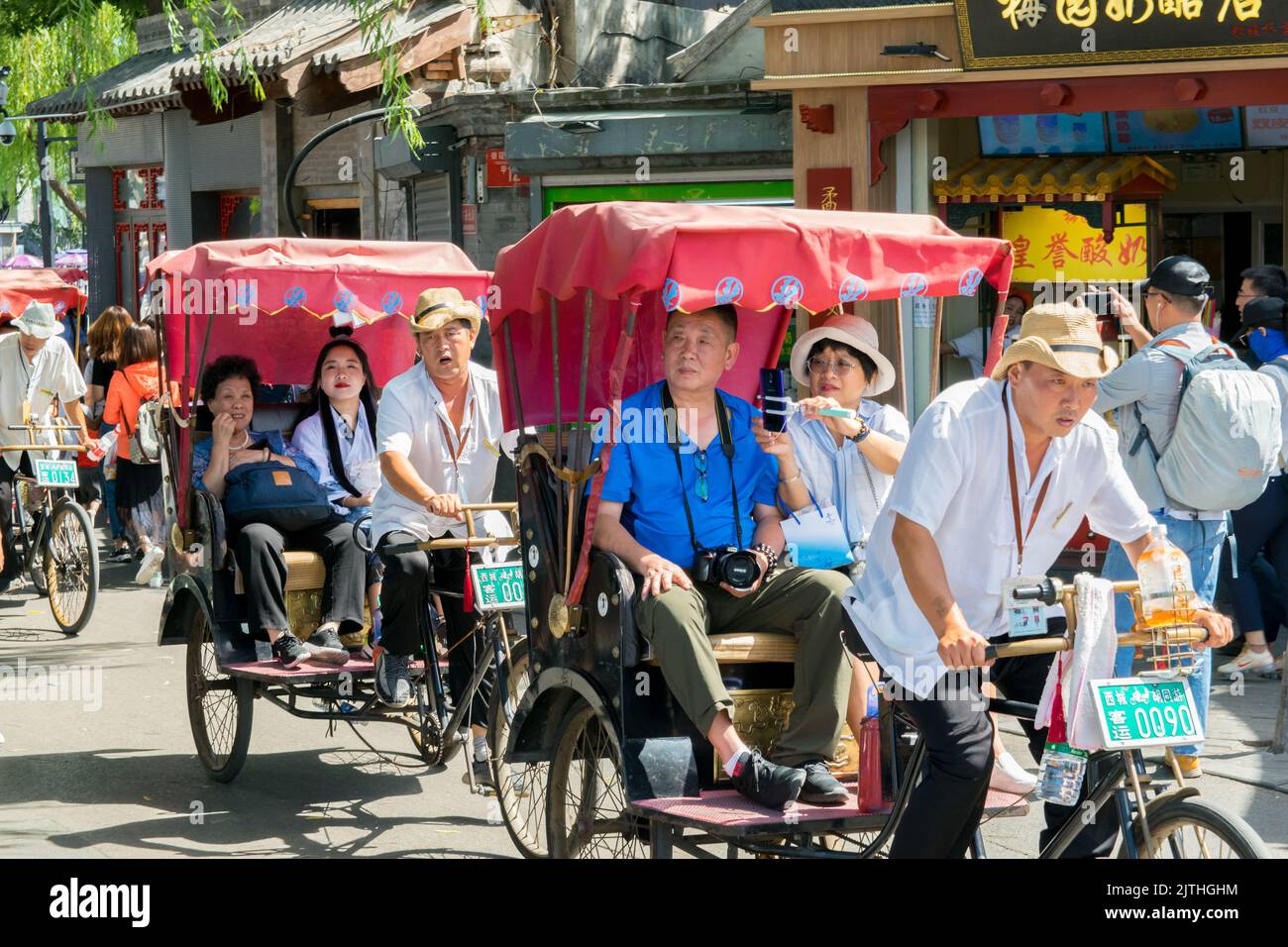 Chinesische Touristen werden in einer Rikscha in der Nähe des Qianhai-Sees in Peking geführt. Stockfoto