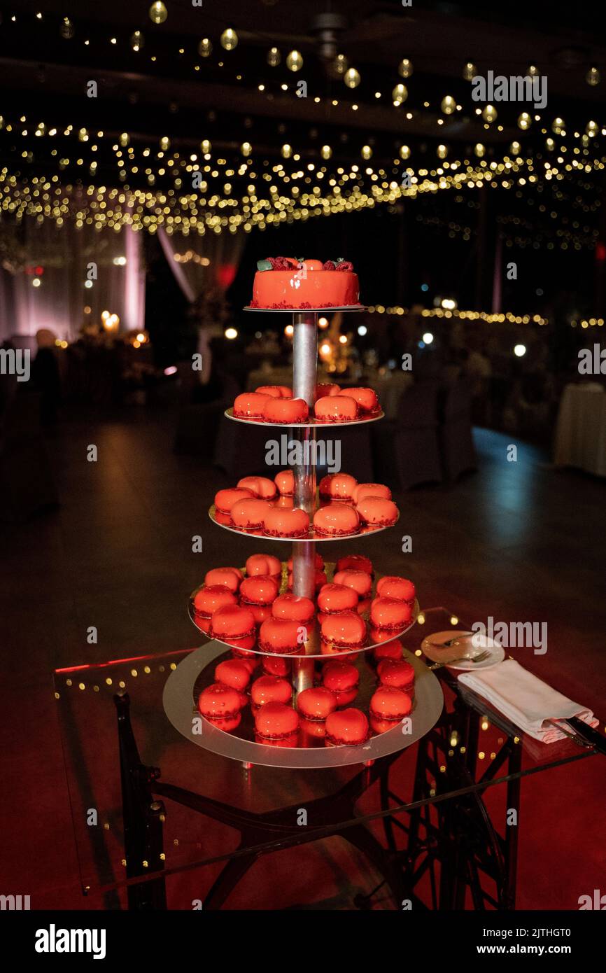 Eine rote Hochzeitstorte mit kleinen herzförmigen Mousse-Kuchen Stockfoto