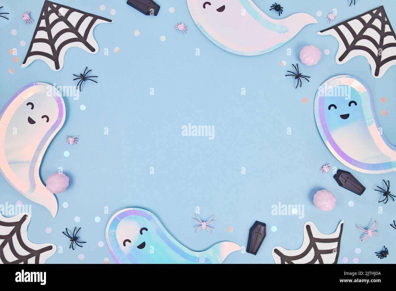 Niedlicher, pastellfarbener Halloween Partyrahmen mit geisterförmigen Tellern, Spinnennetz Servietten und Konfetti auf blauem Hintergrund Stockfoto