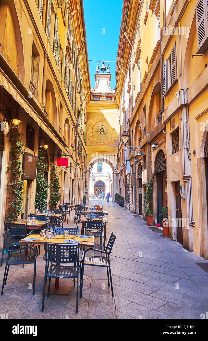 Die schmale Gasse der Via Cesare Beccaria, gesäumt von historischen Gebäuden und mit Blick auf mittelalterliche astronomische Uhr und Restaurants im Freien, Brescia Stockfoto