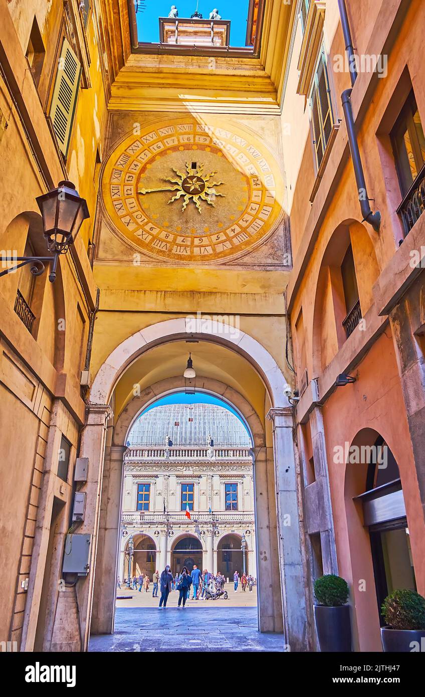 Die mittelalterliche malerische Torre dell'Orologio astronomische Uhr von der Via Cesare Beccaria Straße mit Loggia-Palast, durch den Bogen gesehen, Brescia, Italien Stockfoto