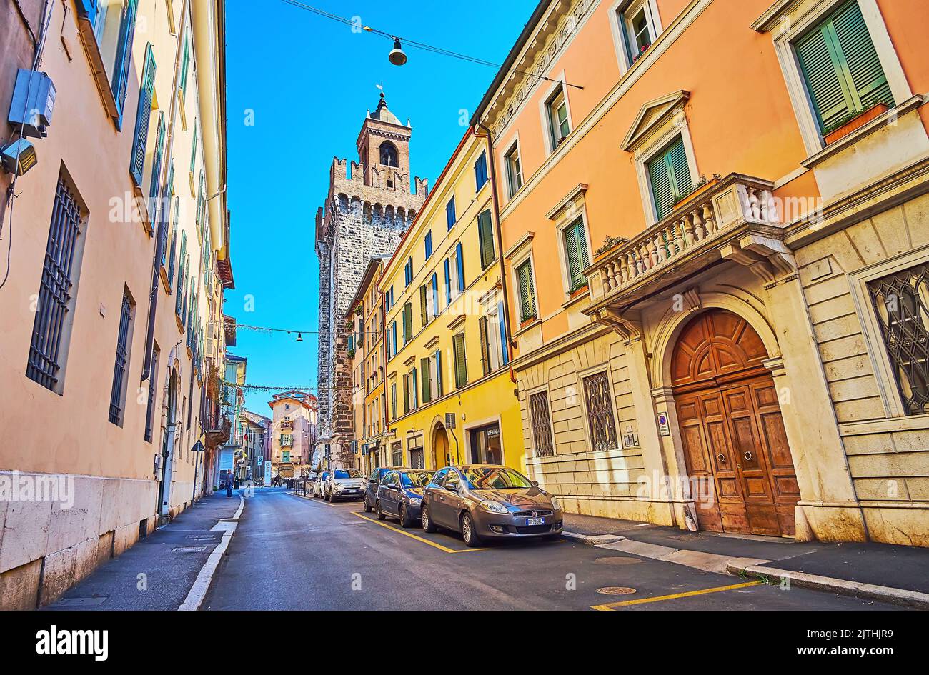 BRESCIA, ITALIEN - 10. APRIL 2022: Via della Pace Straße mit historischen Häusern und mittelalterlichem Pallata Turm aus Stein mit dekorativen Zinnen im Hintergrund Stockfoto