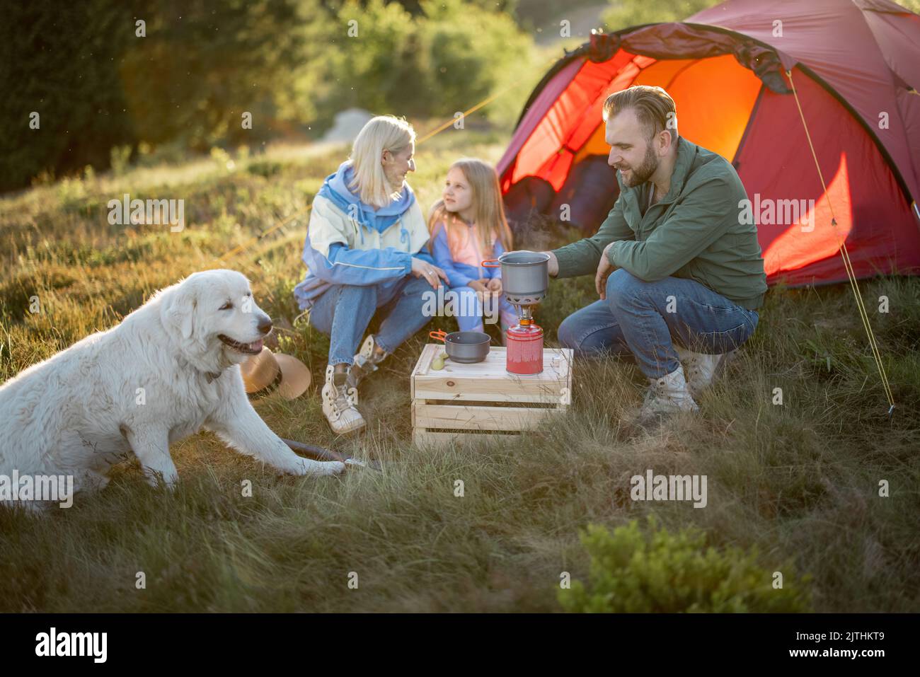 Pärchen mit Mädchen picknicken auf dem Campingplatz in den Bergen Stockfoto