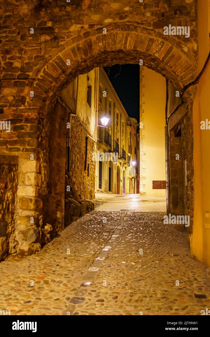 Malerische Gasse mit Steinbogen, der Eingang zur Stadt Besalu bei Nacht, Girona, Spanien gibt. Stockfoto