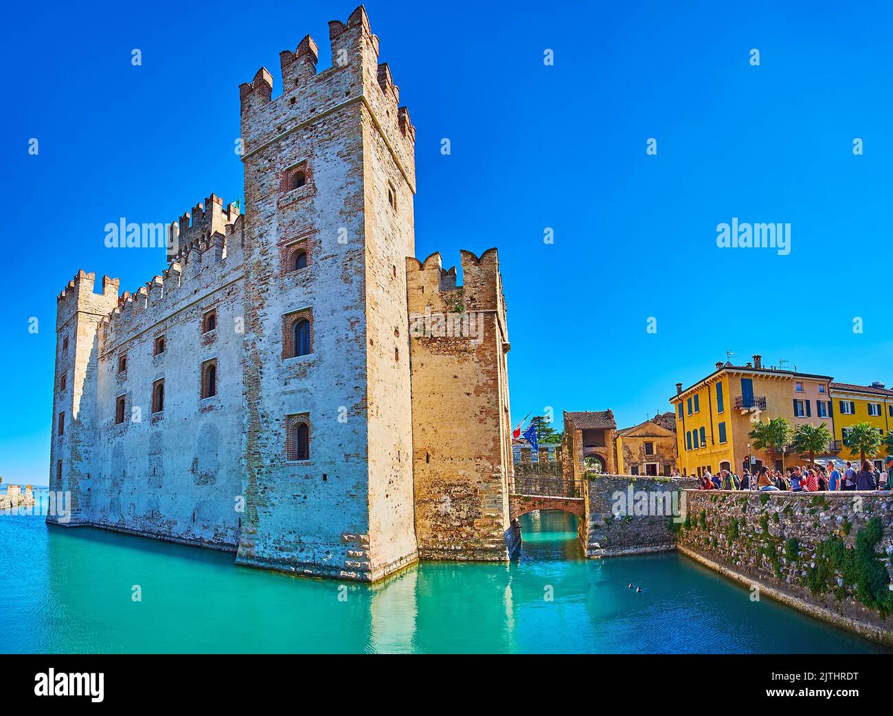 BRESCIA, ITALIEN - 10. APRIL 2022: Die hohen Türme und erhaltenen Stadtmauern des mittelalterlichen Castello Scaligero, umgeben von Graben und alten Stadthäusern, auf Einem Stockfoto