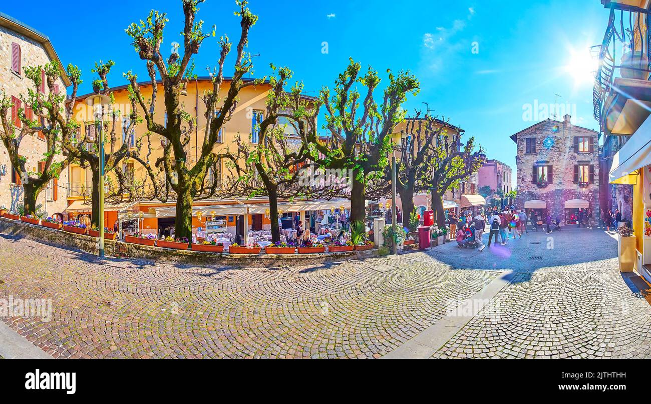 Panorama der alten engen Via San Salvatore Straße mit ausgebreiteten Bäumen, Terrassen von Cafés und Restaurants vor den historischen Häusern von Sirmio Stockfoto