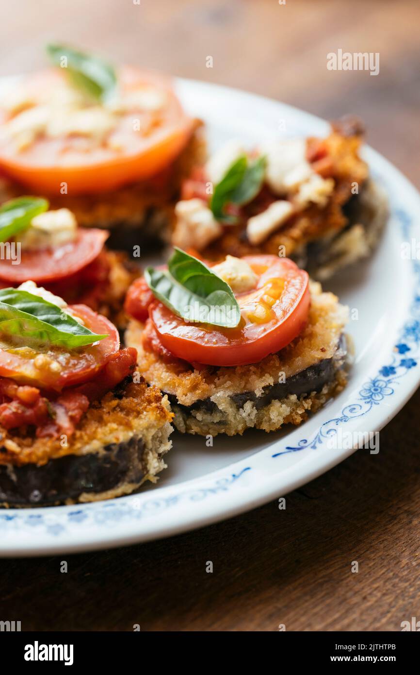 Panierte Auberginen-Stapel mit Tomatensauce, Tomatenscheibe und veganer Feta Stockfoto