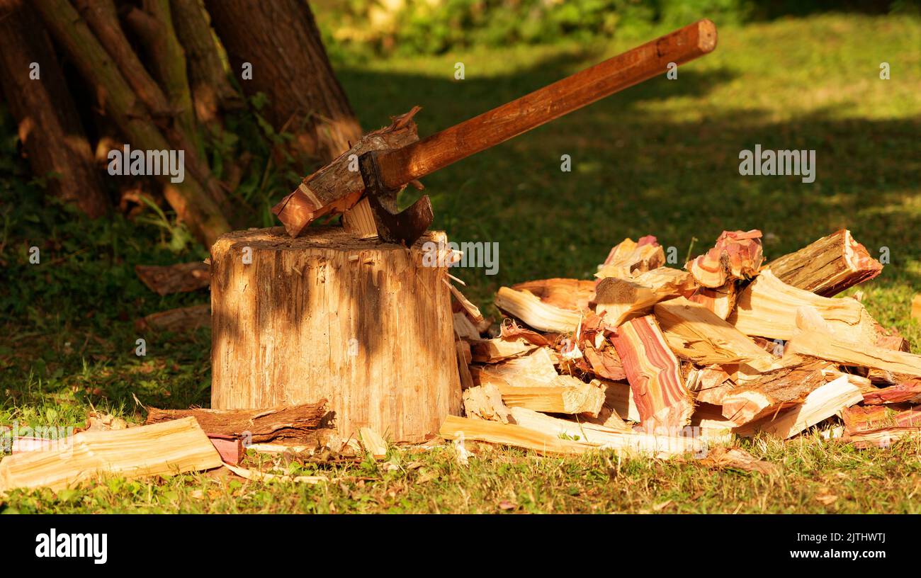 Gehacktes Brennholz neben einem Holzdeck mit einer alten Axt Stockfoto