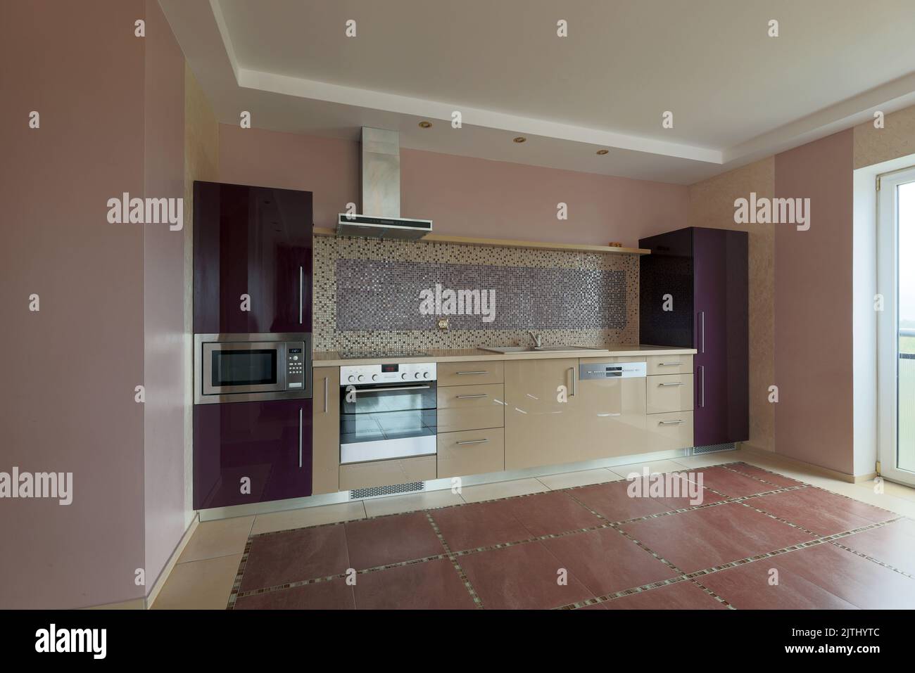 Innenansicht einer beigefarbenen und violetten Wohnküche mit Geräten Stockfoto