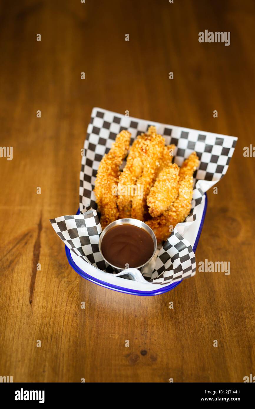 Hähnchenfinger mit Ketchup-Sauce auf einem Teller auf einem Holztisch Stockfoto