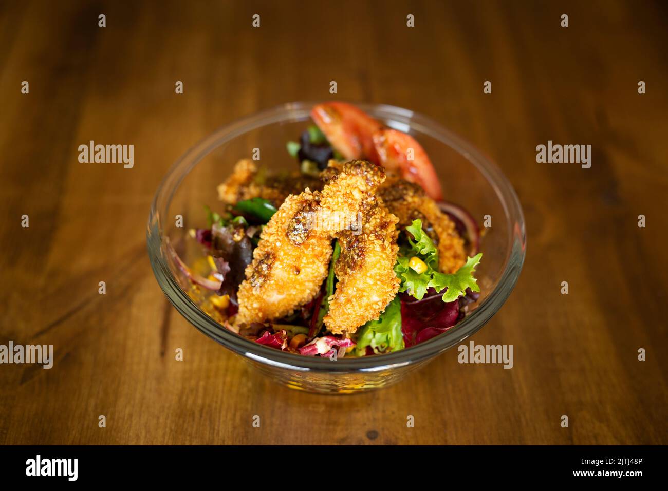 Grüner Salat mit Hähnchenfingern in einer großen Schüssel auf einem Holztisch Stockfoto