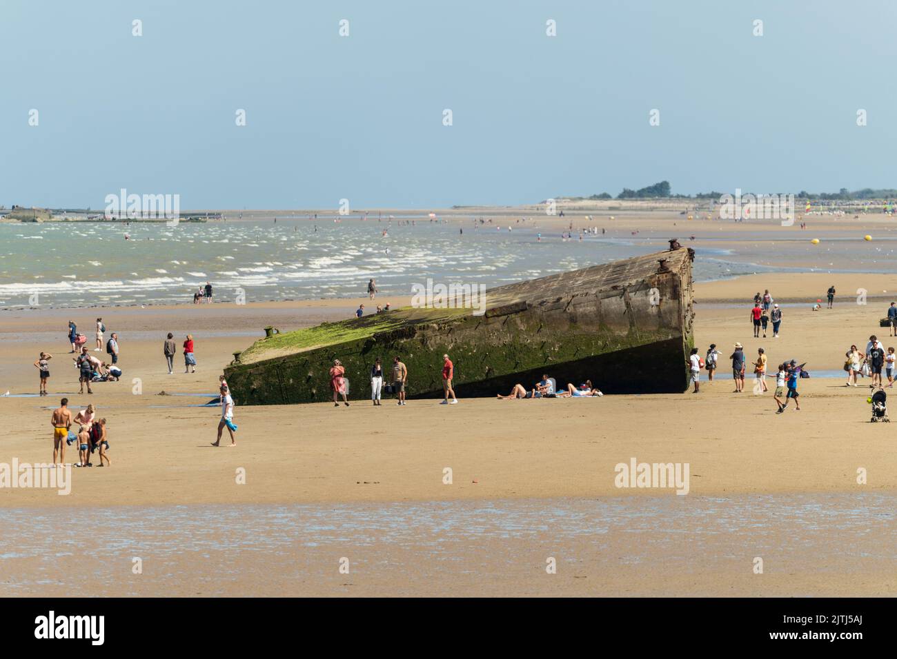 Touristen erkunden die Überreste des Hafens von Mulberry am Strand von Arromanches-les-Bains Stockfoto