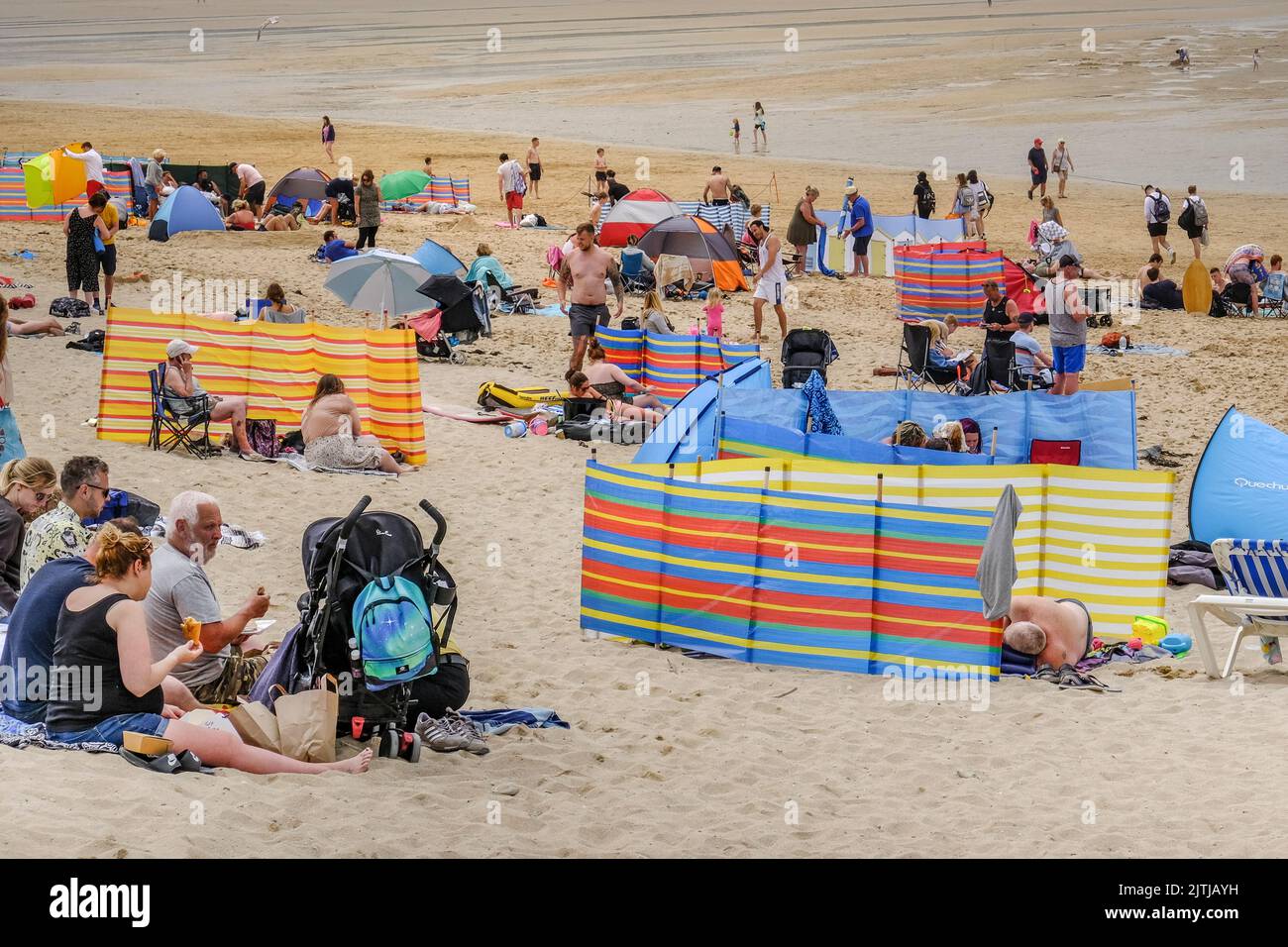 An einem der heißesten Tage des Jahres in Großbritannien genossen Urlauber am Fistral Beach den warmen, nebligen Sonnenschein und die willkommene, kühle Meeresbrise auf dem See Stockfoto