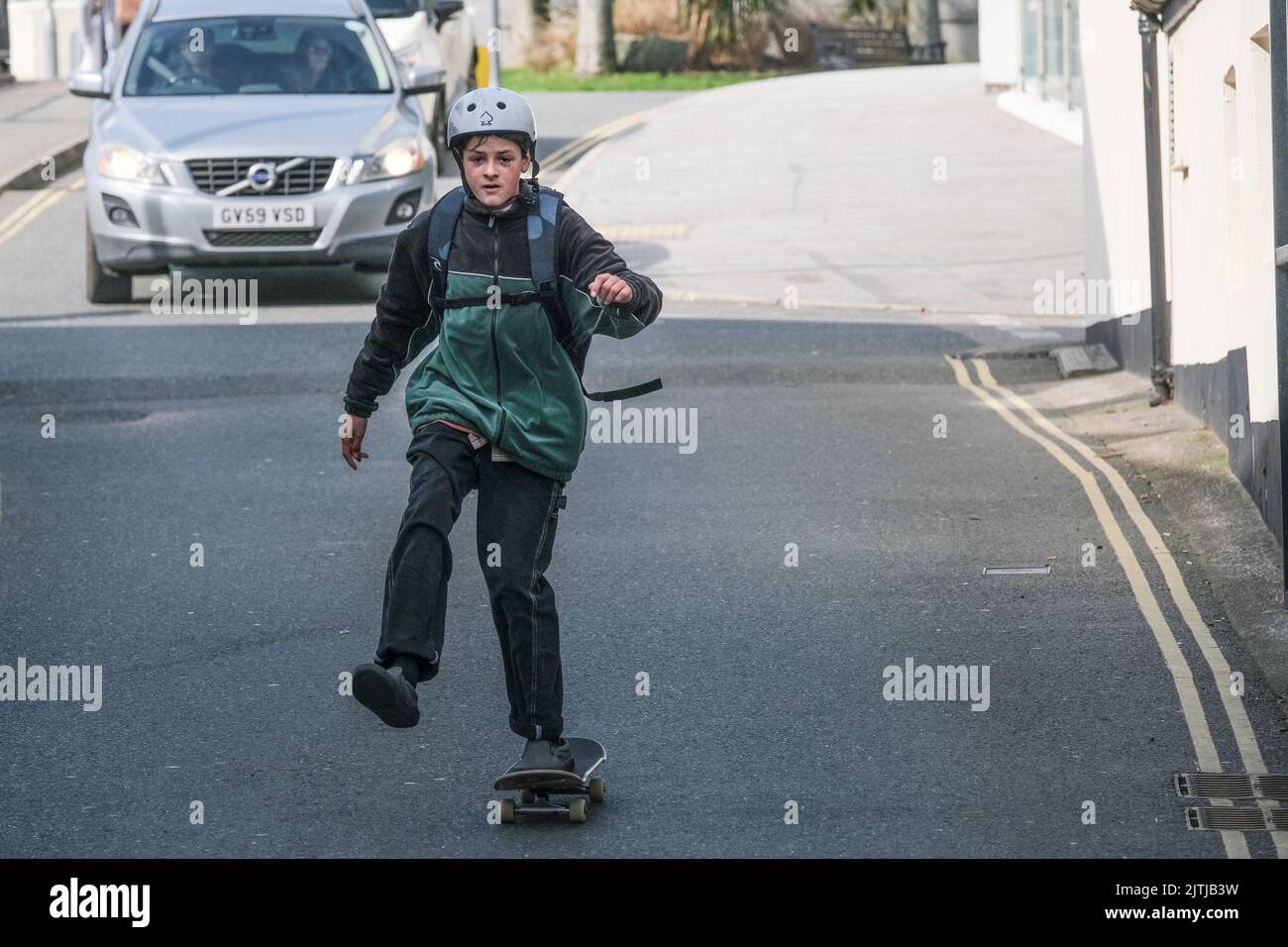 Ein junger Skateboarder, der den Verkehr auf der Hauptstraße im Stadtzentrum von Newquay in Cornwall ignoriert. Stockfoto