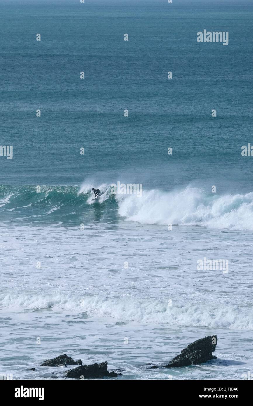 Ein eineinesigers Surfer, der in der Fistral Bay in Newquay in Cornwall in England im Vereinigten Königreich auf einer Welle reitet. Stockfoto